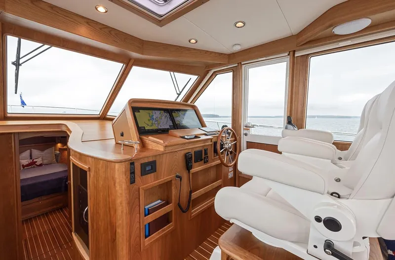 Slide: The Image of Interior of 2026 Sabre 45 Salon Express yacht with wooden helm and white captain's chair. - 7