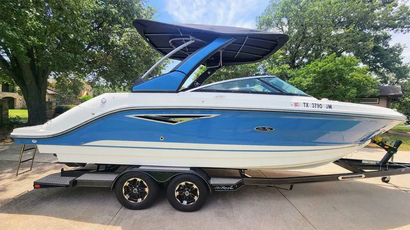 Slide: The Image of 2021 Sea Ray SLX 250 boat on trailer, blue and white, parked outdoors. - 1