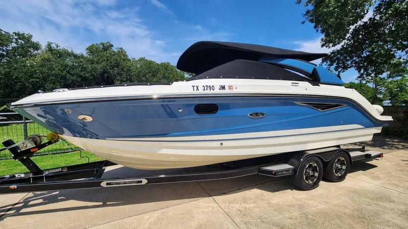 Slide: The Image of 2021 Sea Ray SLX 250 boat on trailer, parked outdoors under clear sky. - 33