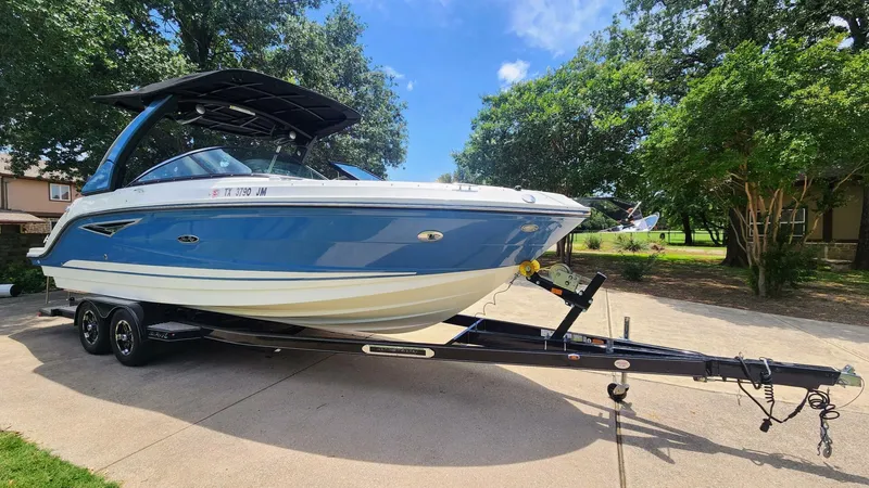 Slide: The Image of 2021 Sea Ray SLX 250 boat on trailer, parked outdoors, surrounded by trees. - 8