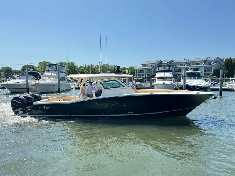 The Image of 2018 Scout 380 LXF boat cruising in a marina with other boats docked nearby. - 0