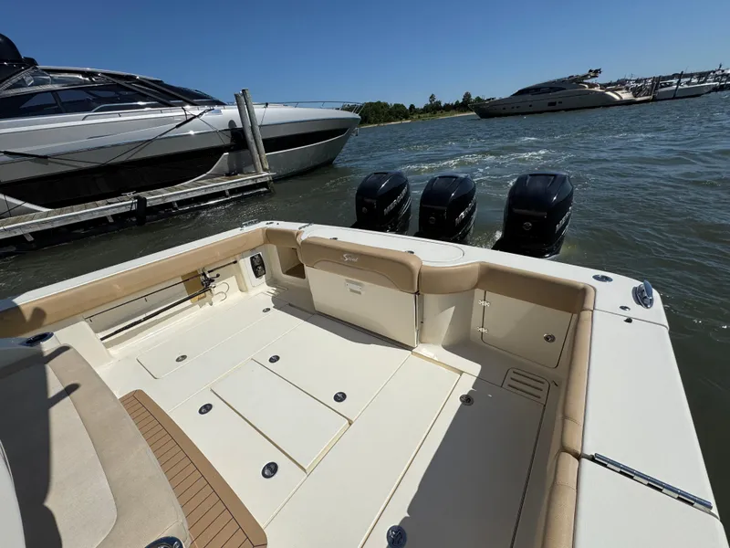 Slide: The Image of 2018 Scout 380 LXF boat with triple Mercury engines docked near luxury yachts. - 13