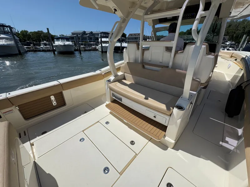 Slide: The Image of 2018 Scout 380 LXF boat interior with seating and storage, docked at a marina. - 15