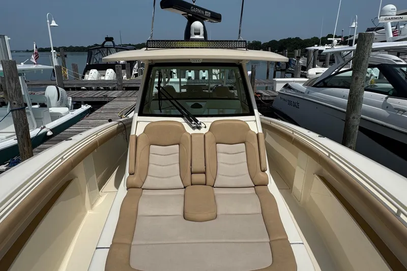 Slide: The Image of 2018 Scout 380 LXF boat with cushioned seating at a marina dock. - 16