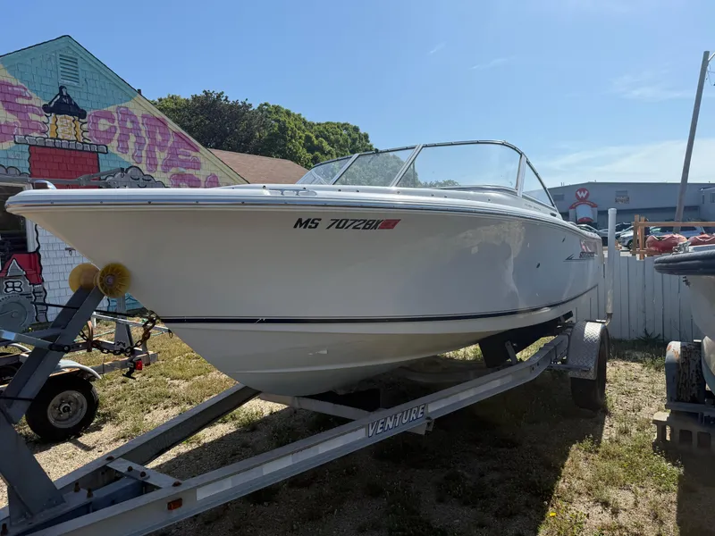 Slide: The Image of 2012 Sea Hunt Escape 188LE boat on trailer, parked outdoors near graffiti wall. - 2