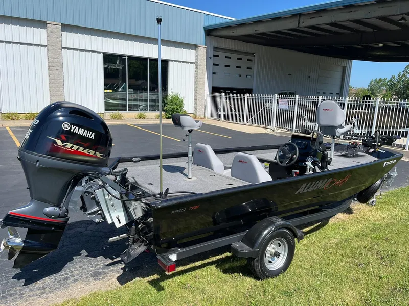 Slide: The Image of 2022 Alumacraft Pro 175 boat with Yamaha VMAX engine, parked outside a building. - 2