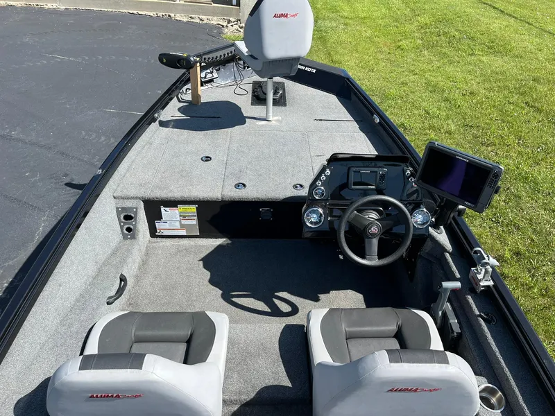 Slide: The Image of 2022 Alumacraft Pro 175 boat interior with steering console and seating on a sunny day. - 5