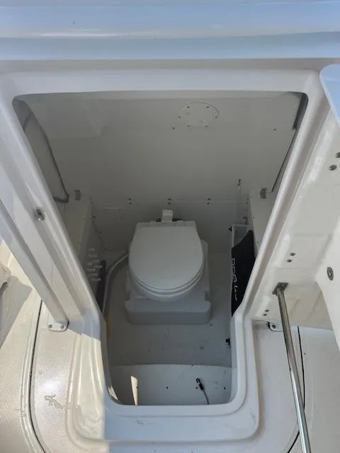Slide: The Image of 2022 Robalo R230 Center Console boat interior with a compact marine toilet. - 19
