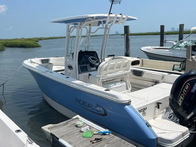 Slide: The Image of 2022 Robalo R230 Center Console boat docked by the water. - 2