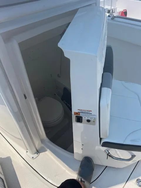 Slide: The Image of 2022 Robalo R230 Center Console boat interior with seating and compact toilet. - 20