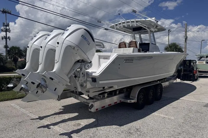 Slide: The Image of 2025 Jupiter 380 LS boat on trailer with twin Yamaha engines, parked outdoors. - 2