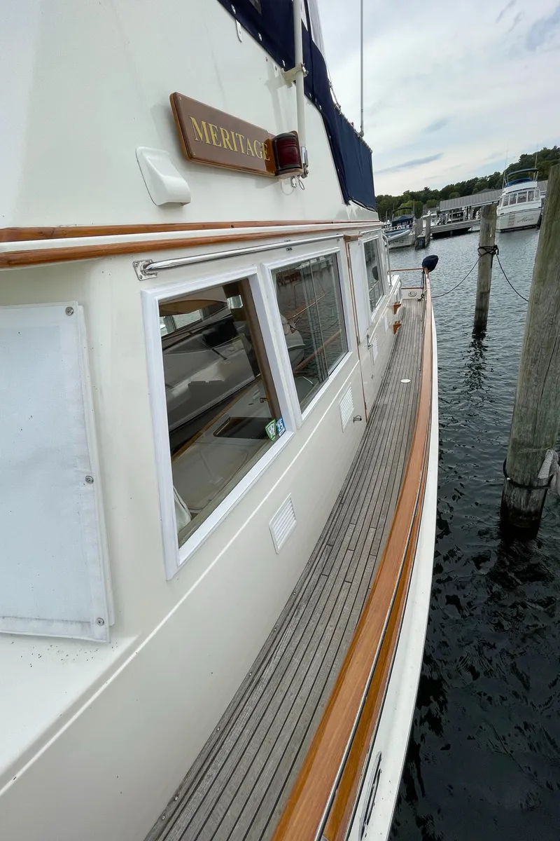 Slide: The Image of 1990 Grand Banks 42 Classic yacht docked, showcasing elegant wooden deck and sleek design. - 17