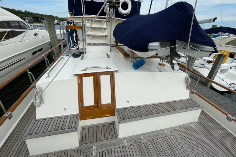 Slide: The Image of 1990 Grand Banks 42 Classic yacht deck with covered equipment and wooden accents. - 30