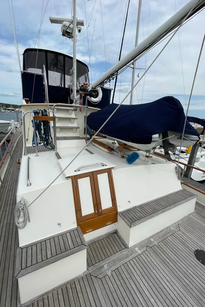 Slide: The Image of 1990 Grand Banks 42 Classic yacht deck with covered equipment and wooden accents. - 32