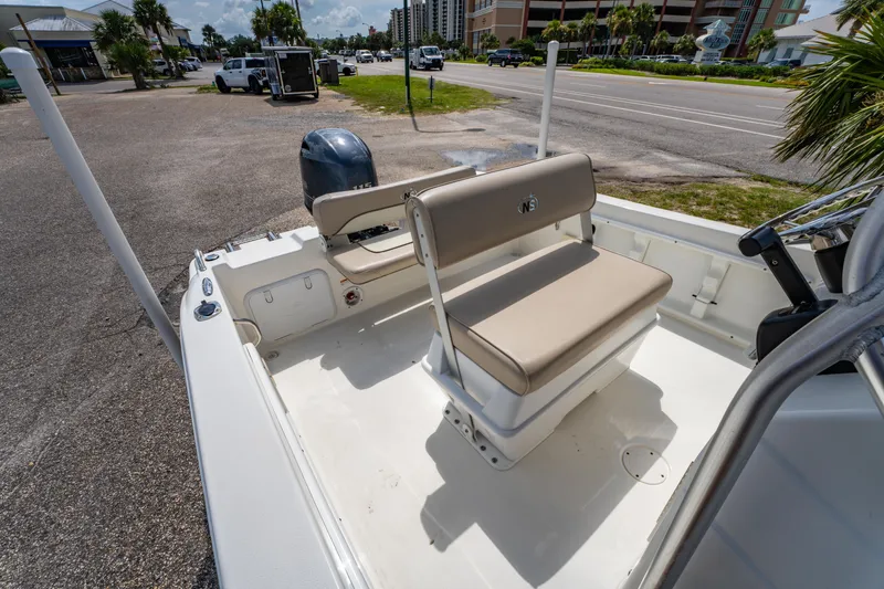 Slide: The Image of 2017 NauticStar 19XS boat interior with seating and motor, parked near a road. - 12