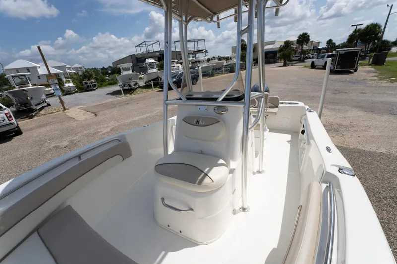 Slide: The Image of 2017 NauticStar 19XS boat interior with seating and console, parked outdoors under a sunny sky. - 17