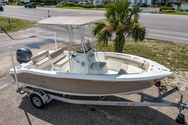 Slide: The Image of 2017 NauticStar 19XS boat on trailer, parked near road with palm tree background. - 21