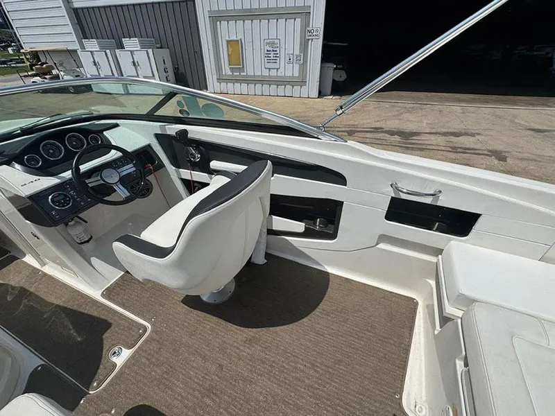 Slide: The Image of 2014 Sea Ray 240 Sundeck cockpit with steering wheel and seating, docked at marina. - 10