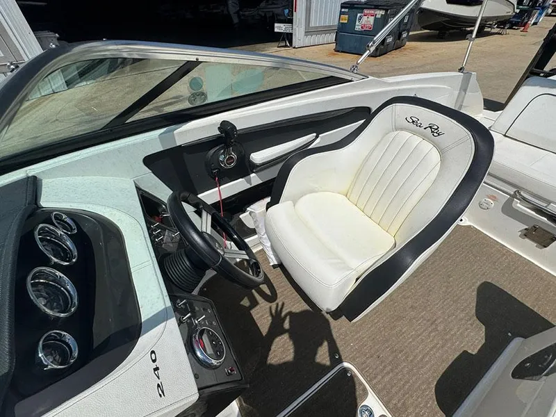 Slide: The Image of 2014 Sea Ray 240 Sundeck cockpit with steering wheel and white captain's chair. - 14