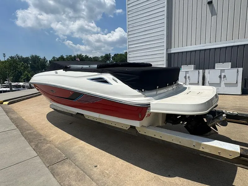 Slide: The Image of 2014 Sea Ray 240 Sundeck boat on trailer, red and white, covered, outdoors. - 2
