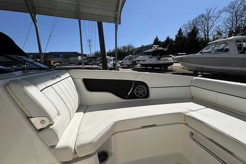 Slide: The Image of 2014 Sea Ray 240 Sundeck interior with white seating and speaker, docked under shelter. - 21