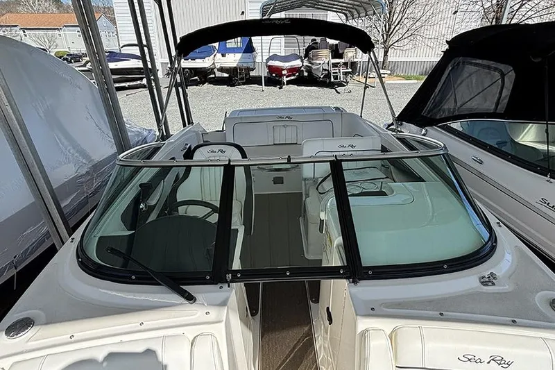 Slide: The Image of 2014 Sea Ray 240 Sundeck boat with open cockpit and windshield, docked under a canopy. - 27