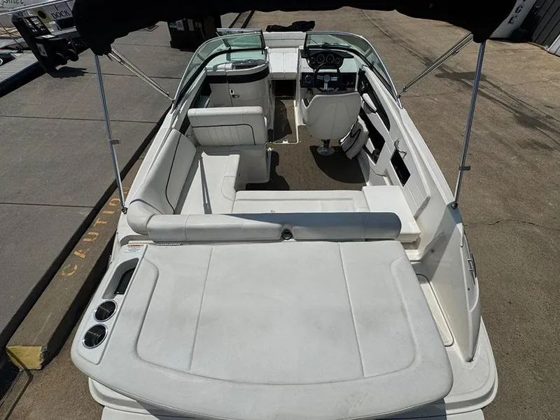 Slide: The Image of 2014 Sea Ray 240 Sundeck interior with seating and steering wheel, docked on pavement. - 7