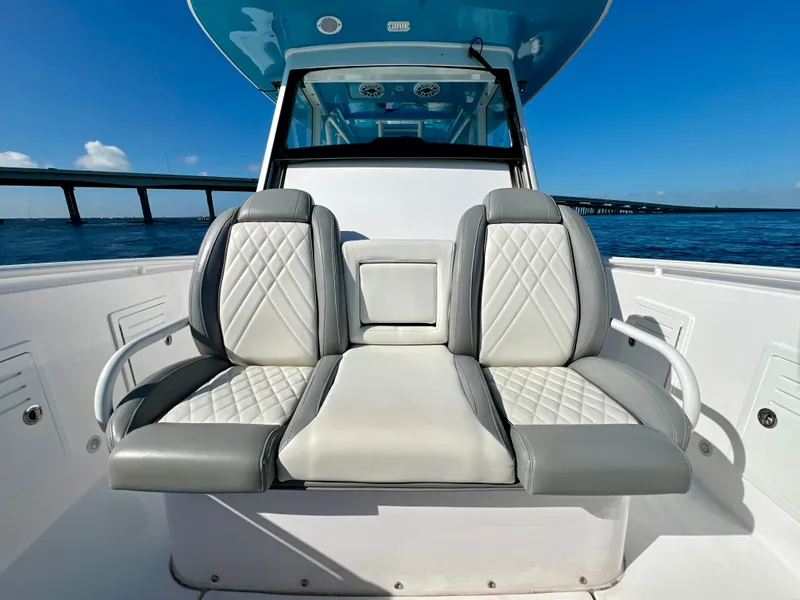 Slide: The Image of 2023 Everglades 365 Center Console boat with luxurious seating, ocean view, and bridge in background. - 15