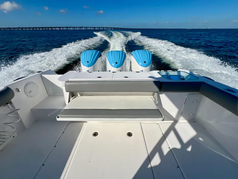Slide: The Image of 2023 Everglades 365 Center Console boat cruising on open water, showcasing triple engines. - 25