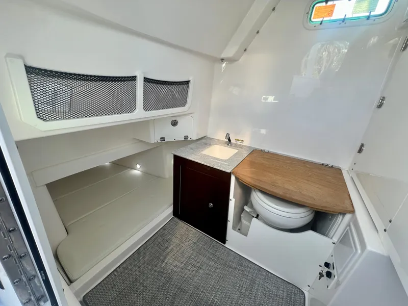 Slide: The Image of 2023 Everglades 365 Center Console cabin interior with sink, toilet, and storage. - 27