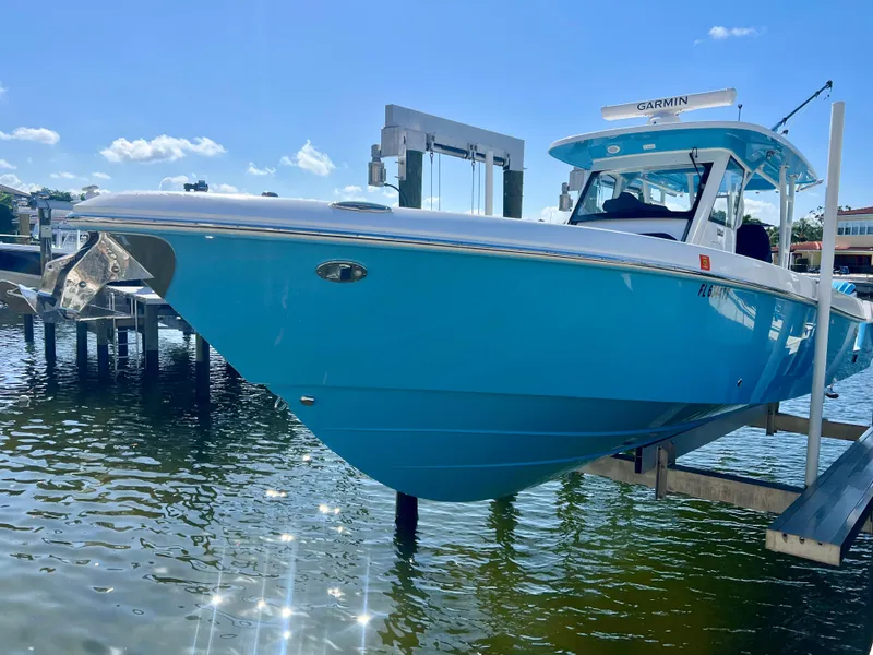 Slide: The Image of 2023 Everglades 365 Center Console boat docked, featuring a sleek blue hull and modern design. - 35