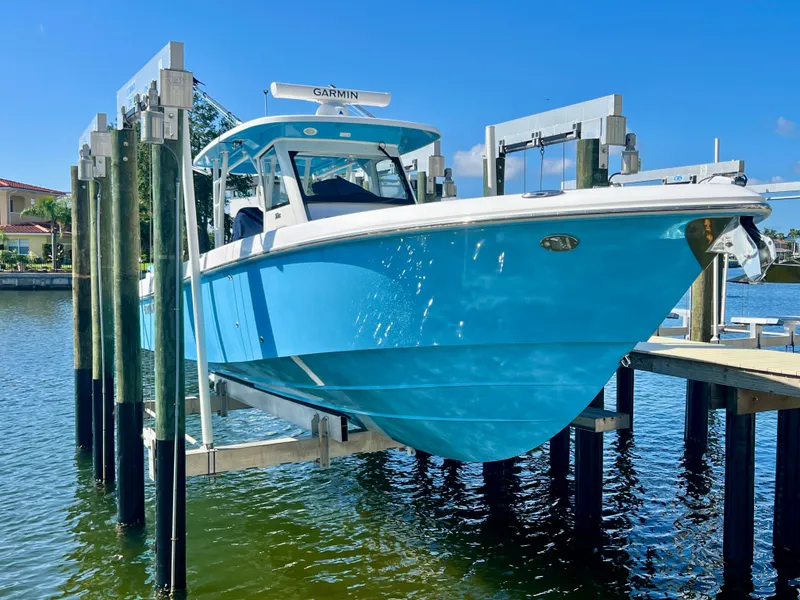 Slide: The Image of 2023 Everglades 365 Center Console boat on lift, vibrant blue hull, sunny day. - 37