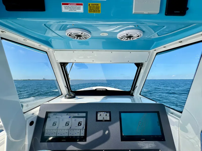 Slide: The Image of 2023 Everglades 365 Center Console boat dashboard with navigation screens, cruising on open water. - 6