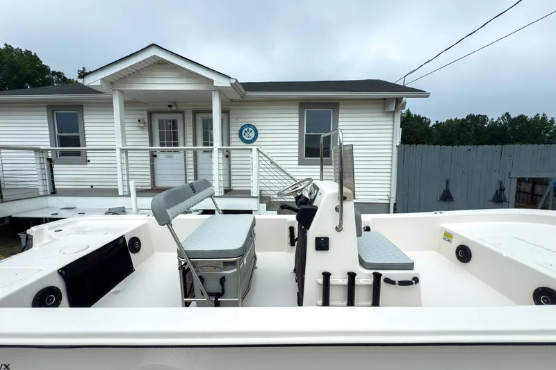 Slide: The Image of 2026 Carolina Skiff E20 JVX CC boat parked near a white house. - 10