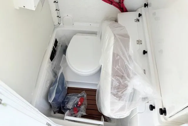 Slide: The Image of 2025 Tidewater 272 CC Adventure boat interior with compact marine toilet setup. - 20