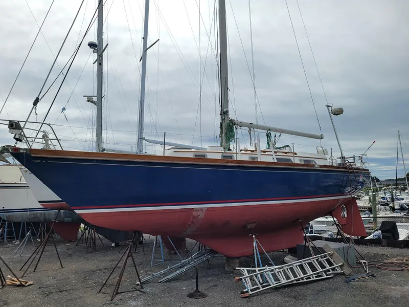 The Image of 1985 Bristol 38.8 sailboat with blue hull and red stripe, docked under clear blue sky. - 0