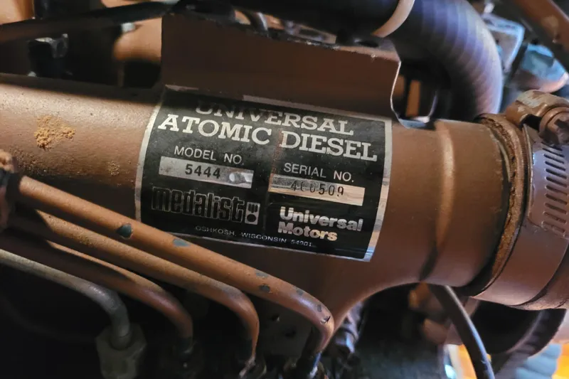 Slide: The Image of Engine compartment of a 1985 Bristol 38.8 sailboat, showing various mechanical components and hoses. - 47