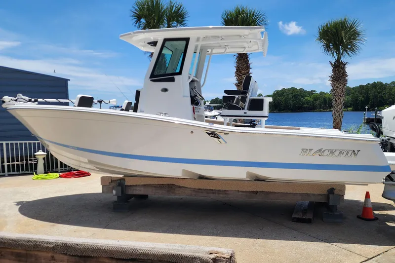 Slide: The Image of 2026 Blackfin 242HB boat on display near a waterfront with palm trees. - 2