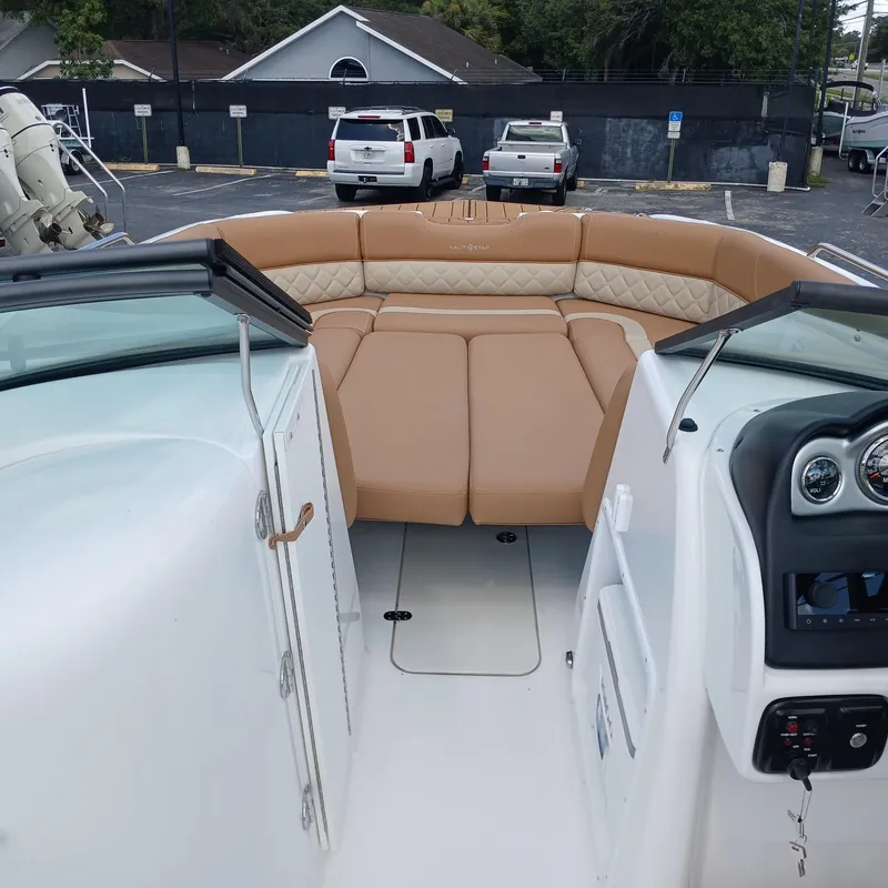 Slide: The Image of 2025 NauticStar 243 DC Deck boat interior with tan seating and modern dashboard. - 4