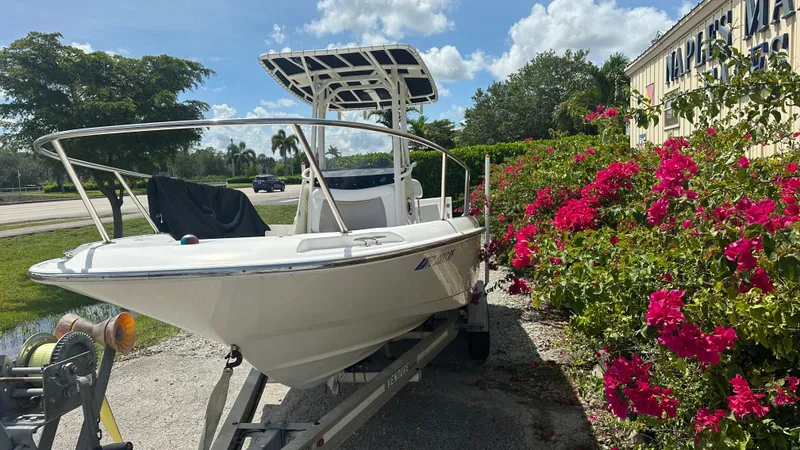 Slide: The Image of 2016 Boston Whaler 240 Dauntless boat on trailer beside vibrant pink flowers. - 12
