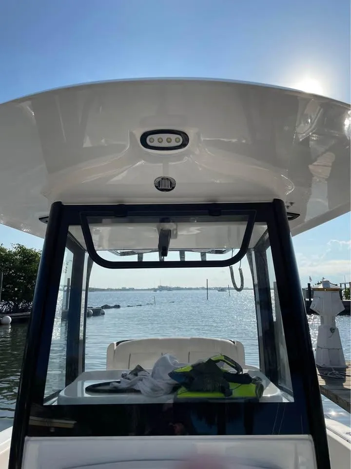 Slide: The Image of 2023 Sea Hunt Ultra 265 SE boat docked with clear sky and water view. - 15