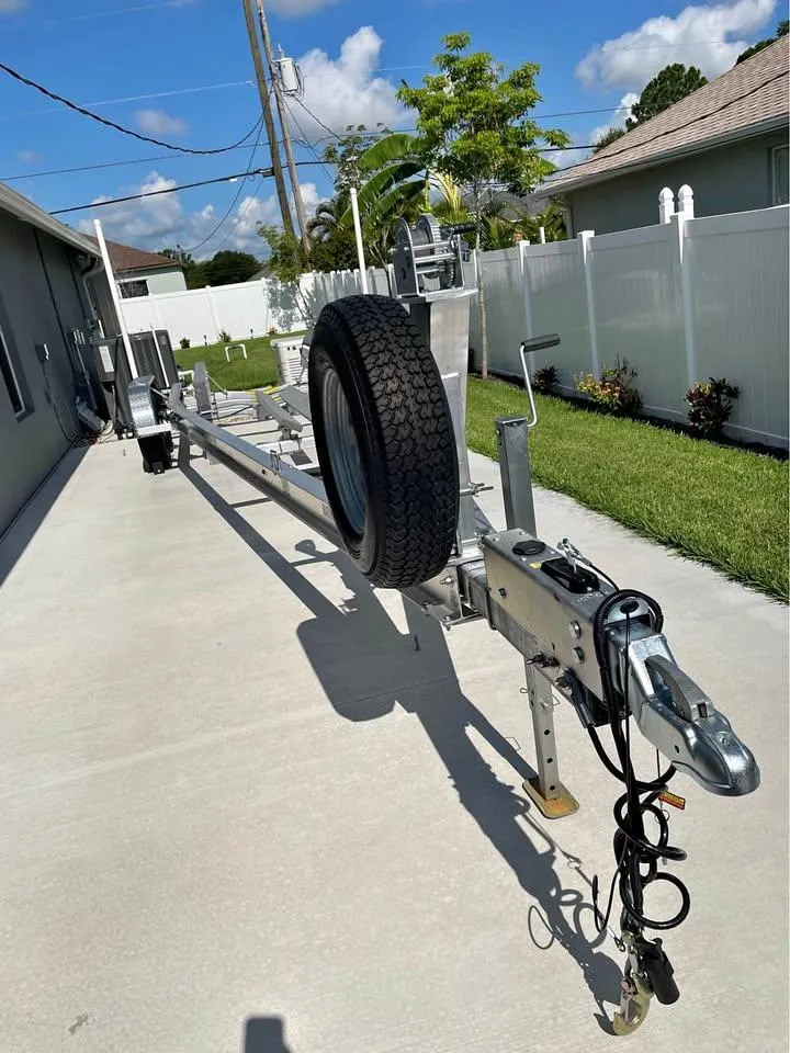 Slide: The Image of Trailer for 2023 Sea Hunt Ultra 265 SE boat parked on concrete driveway. - 5