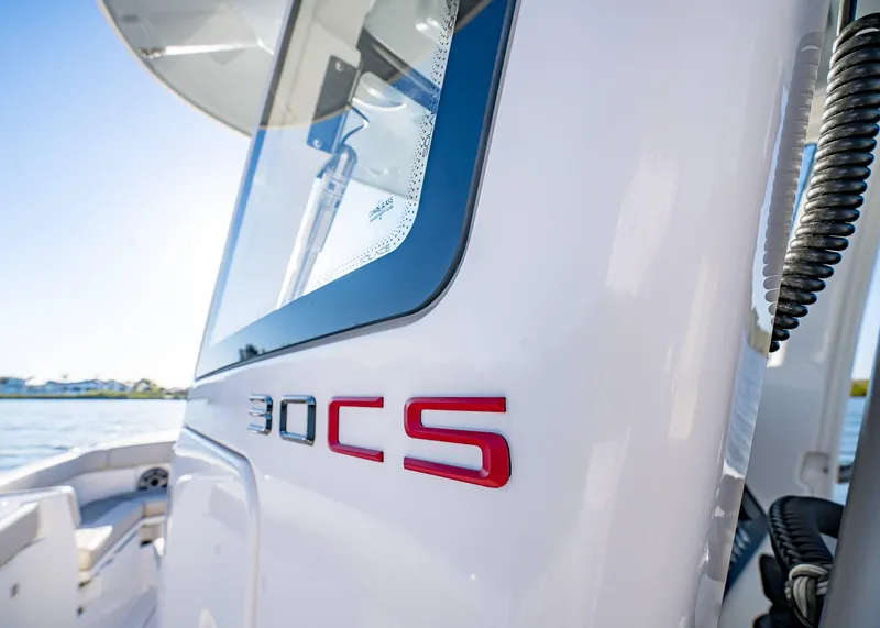 Slide: The Image of 2025 Solace 30 CS boat, close-up of sleek design and logo by the water. - 34