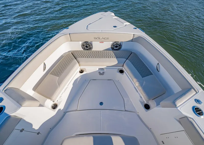 Slide: The Image of 2025 Solace 30 CS boat interior with cushioned seating and speakers on calm water. - 47