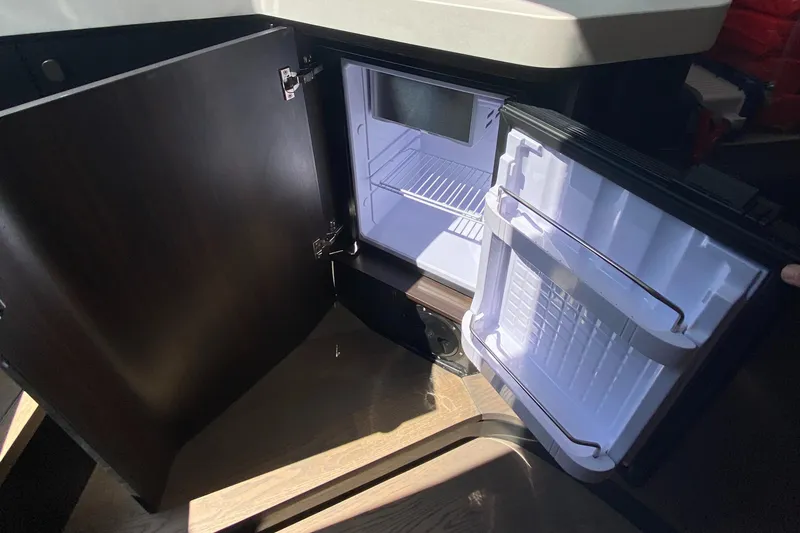 Slide: The Image of Open mini fridge inside 2022 Fairline F//Line 33 yacht, showcasing interior storage space. - 15