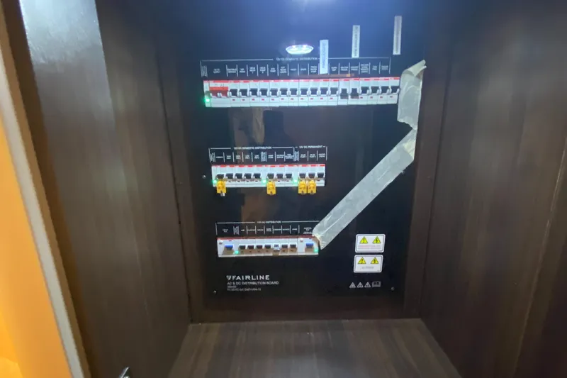 Slide: The Image of Electrical panel inside 2022 Fairline F//Line 33 yacht, featuring circuit breakers and warning labels. - 16