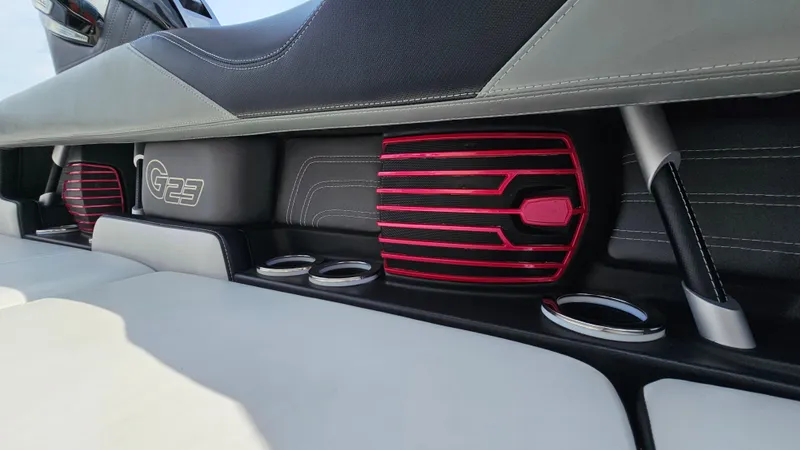 Slide: The Image of 2015 Nautique Super Air G23 interior with red speaker grills and cup holders. - 13