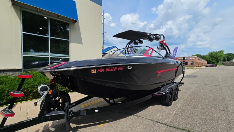 Slide: The Image of 2015 Nautique Super Air G23 boat on trailer, parked near a building. - 2
