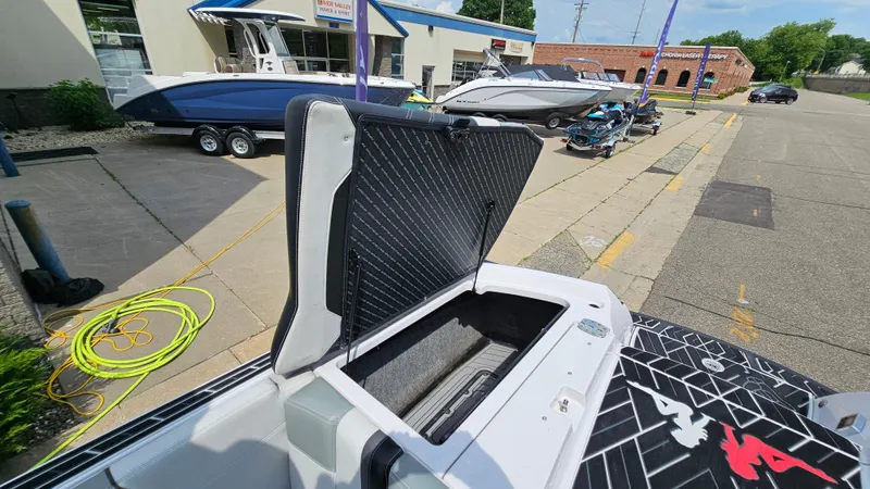 Slide: The Image of 2015 Nautique Super Air G23 boat with open storage compartment, parked outdoors. - 28