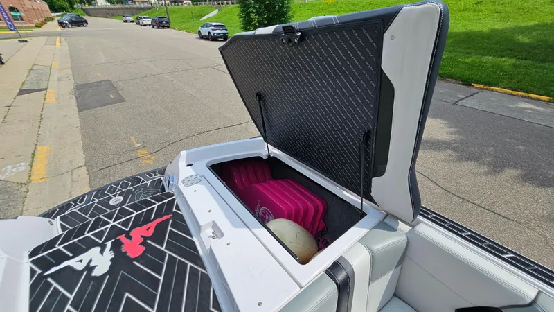 Slide: The Image of Open storage compartment on 2015 Nautique Super Air G23 boat, showing interior contents. - 29